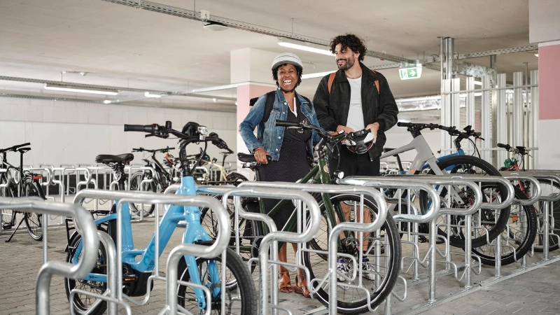 Zwei JobRadler:innen steigen aufs Fahrrad im Fahrradkeller.