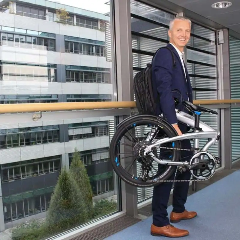 Mitarbeiter mit Faltrad gefaltet - Frank Noe Mitarbeiter mit Faltrad gefaltet - Frank Noe