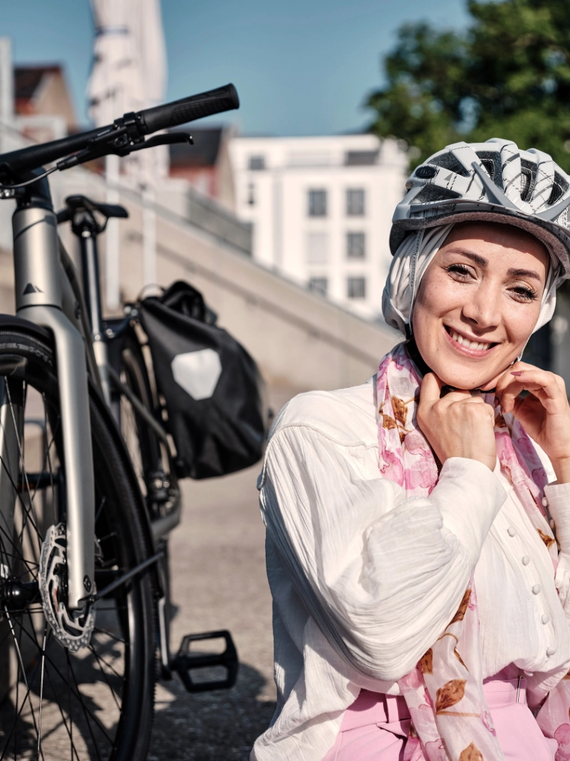 Frau sitzt mit Helm und Fahrrad in der Sonne Frau sitzt mit Helm und Fahrrad in der Sonne