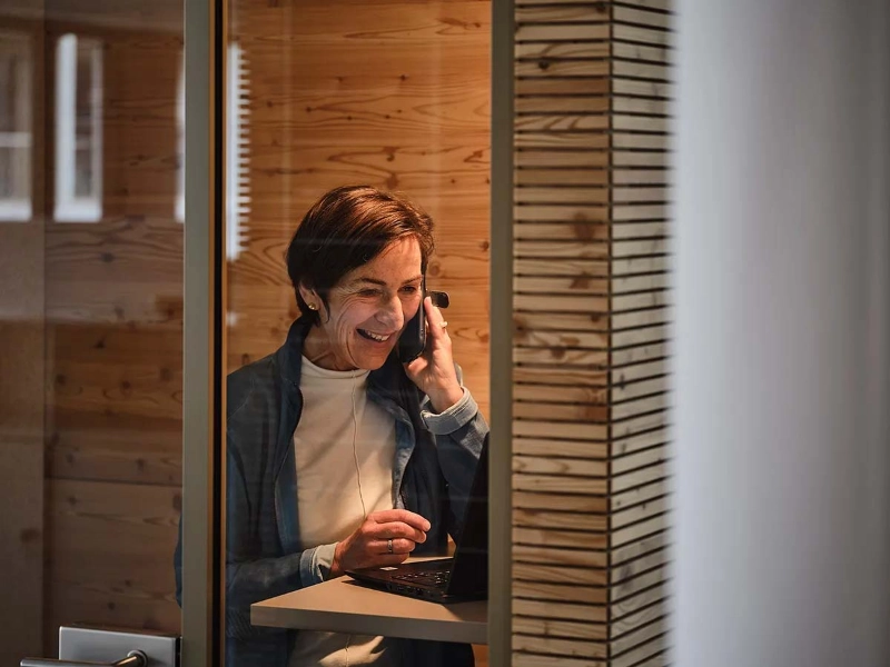 Eine lächelnde ältere Frau sitzt im Büro und telefoniert Eine lächelnde ältere Frau sitzt im Büro und telefoniert