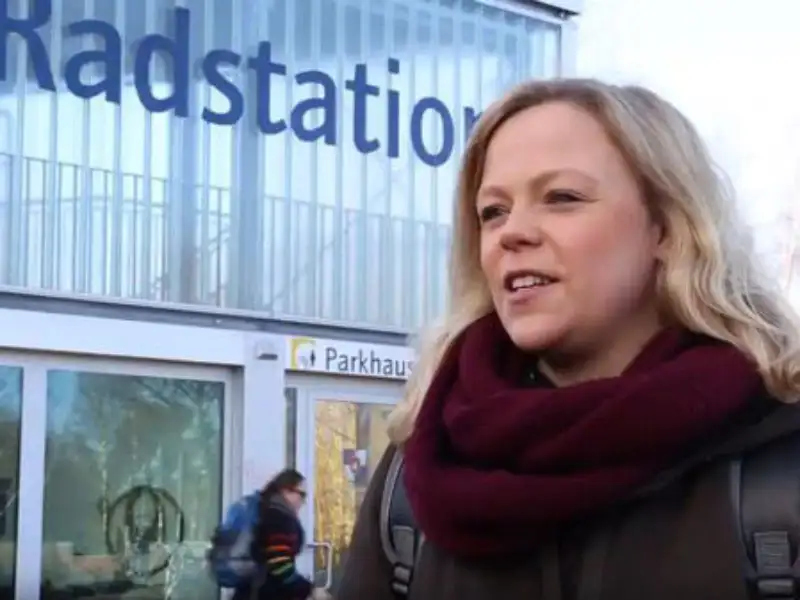 Maraike Kahlstorf von Rewe steht vor einem Gebäude mit der Aufschrift "Radstation". Sie trägt einen roten Wollschal Maraike Kahlstorf von Rewe steht vor einem Gebäude mit der Aufschrift "Radstation". Sie trägt einen roten Wollschal