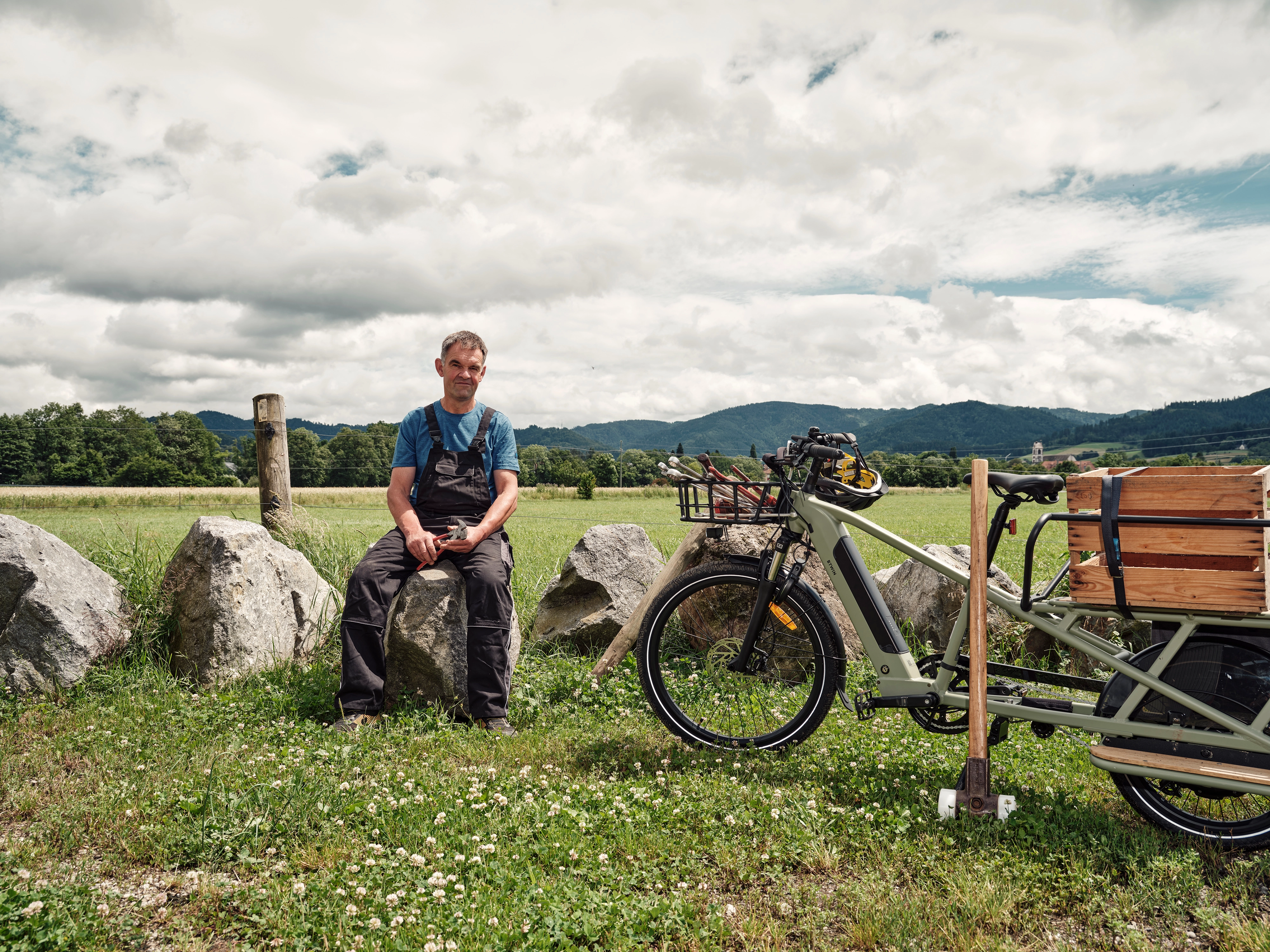 Landwirt sitzt neben Longtail auf Stein und guckt Landwirt sitzt neben Longtail auf Stein und guckt